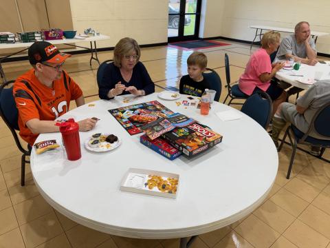 People sitting around a circular table with board games and snacks.