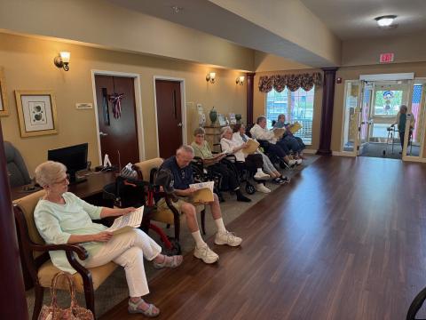 Seniors seated in a waiting room, reading papers.
